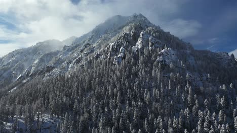 drone aerial view, serene winter landscape, snow capped mountain hills, conifers and clouds on sunny day, drone shot