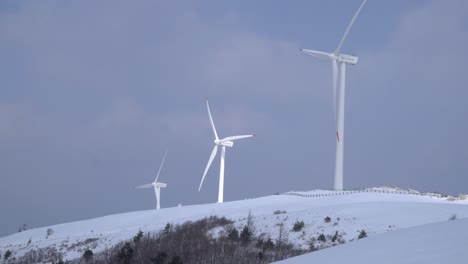 Tres-Molinos-De-Viento-Se-Mueven-Poderosamente,-Estos-Se-Ven-En-La-Montaña-Cubierta-De-Nieve,-Corea-Del-Sur