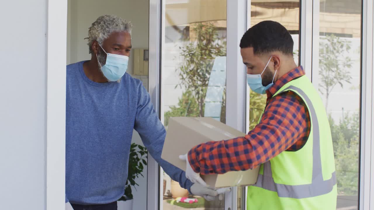 집에서 얼굴 마스크를 쓰고 있는 노인에게 패키지를 배달하는 배달 남자