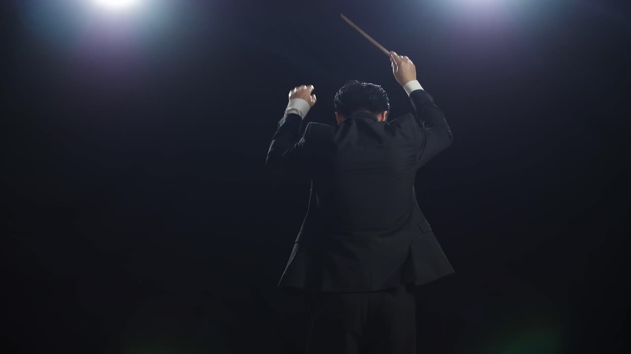 Back View Of Asian Conductor Man Holding A Baton And Showing Gesture Quickly In The Black Studio
