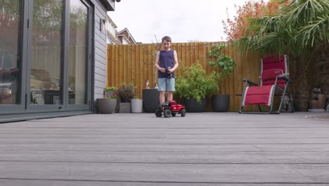 young boy at home outdoors in the garden playing with his rc car, truck, 4 x 4