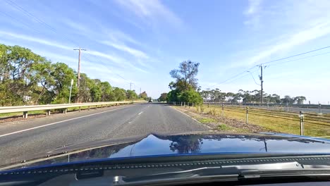 a car travels through geelong's rural roads under clear blue skies, capturing the serene landscape and natural beauty