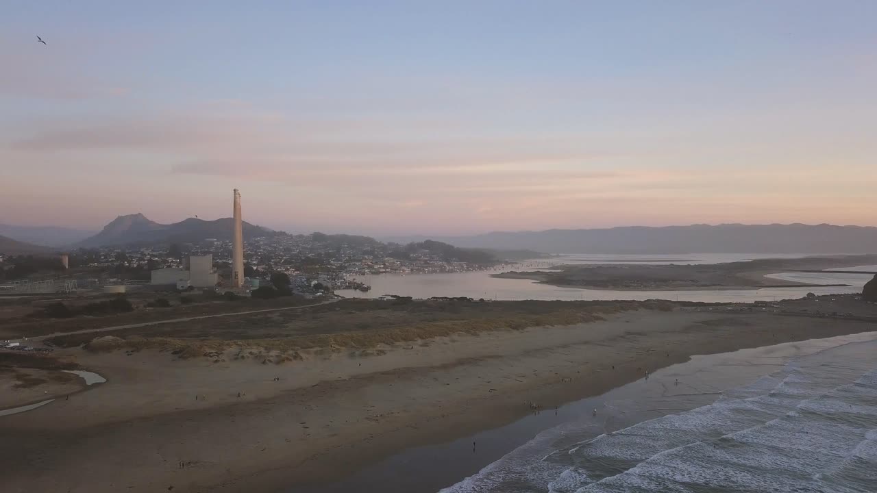 Morro Bay - California, USA. Cinematic right aerial rotation from coast line to industrial power plant. Filmed at sunset on DJI Mavic Pro