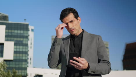 businessman looking at smartphone on street