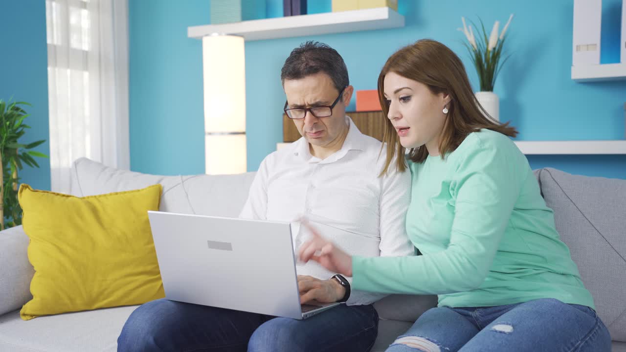 una adolescente ayudando a su padre con el uso de la computadora portátil.