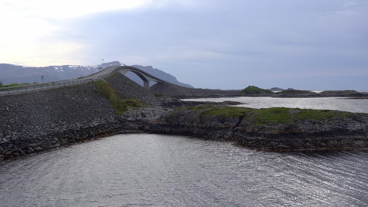 Famous curvy Storseisundet bridge along Atlantic Ocean Road in coastal Norway - Static summer clip with motorcycle and car passing over bridge