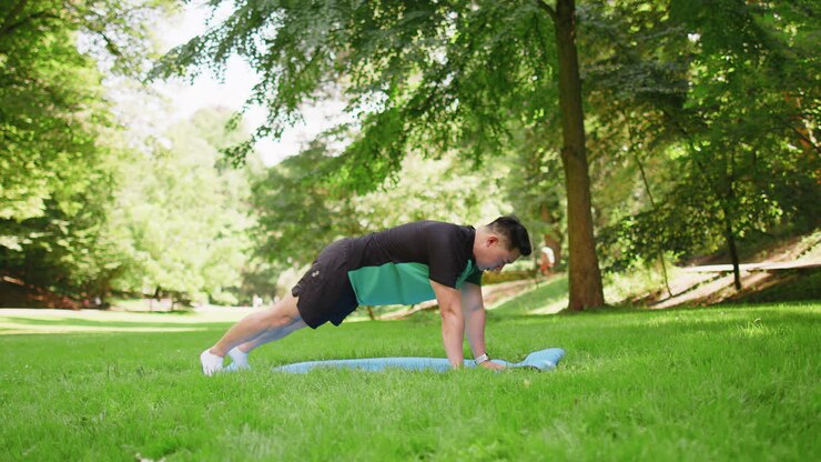 Asian japanese man exercising at park making yoga exercise stretching sports training on mat