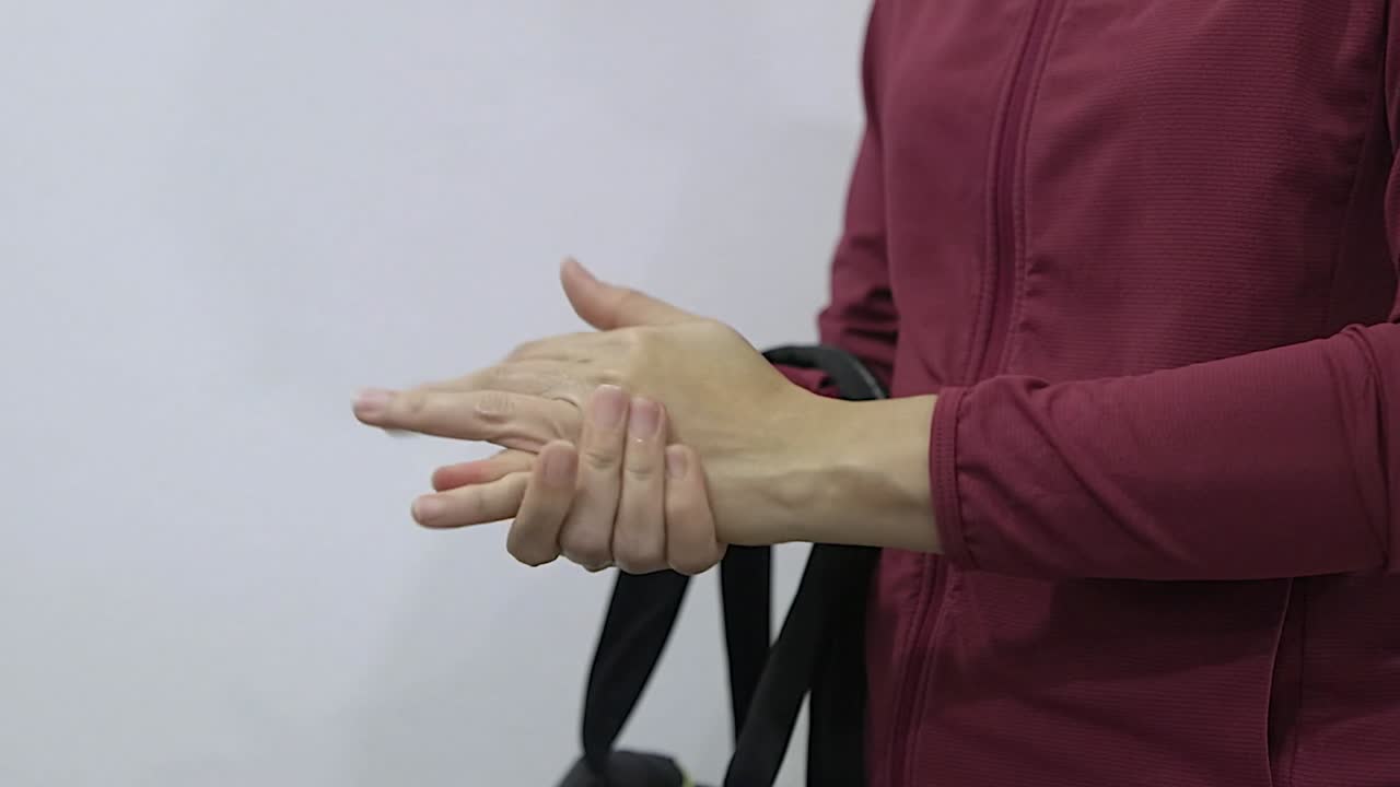 Asian lady disinfecting her hand with a small bottle of non alochol sanitiser and spreads it all over her hands, slow mo footage