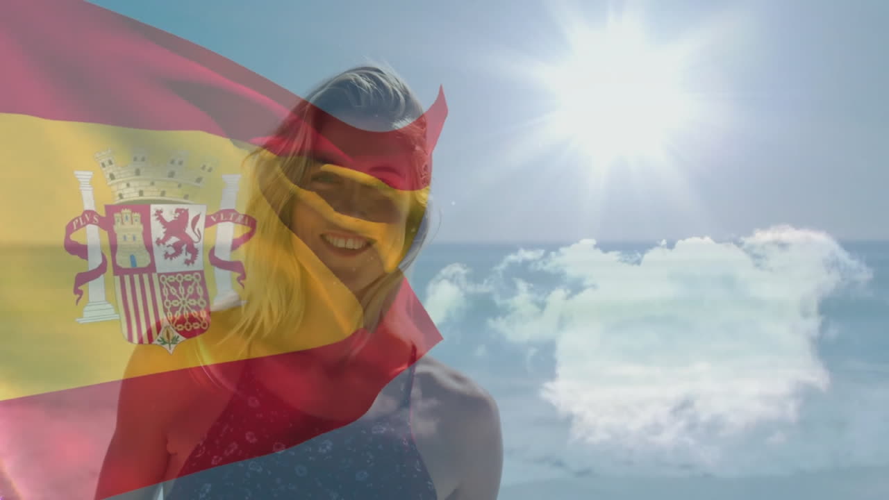 Waving Spanish flag, person standing by sunny beach with clouds in background