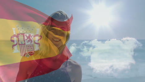 waving spanish flag, person standing by sunny beach with clouds in background