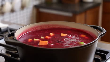 cooking and stirring a vibrant red vegetable soup