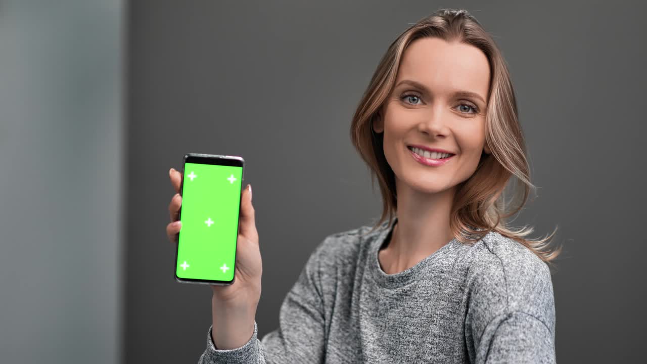 mujer posando con pantalla verde vertical teléfono inteligente aislado. medio primer plano disparado en cámara roja 4k