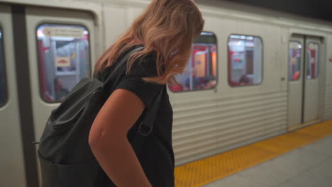 woman waiting for train in subway station on her phone