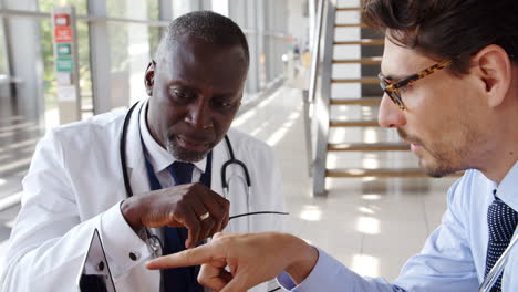 dos médicos varones que se reúnen sentados alrededor de la mesa en el hospital