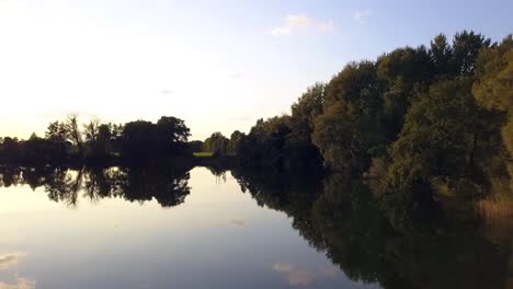 Espectacular-Vuelo-Aéreo-De-Drones-Volar-Hacia-Adelante-Tiro-De-Drones-Levantarse-Lentamente-Tiro-De-Drones-Al-Atardecer-De-Verano-En-Un-Lago-En-Un-Pequeño-Pueblo-En-Brandeburgo-Alemania