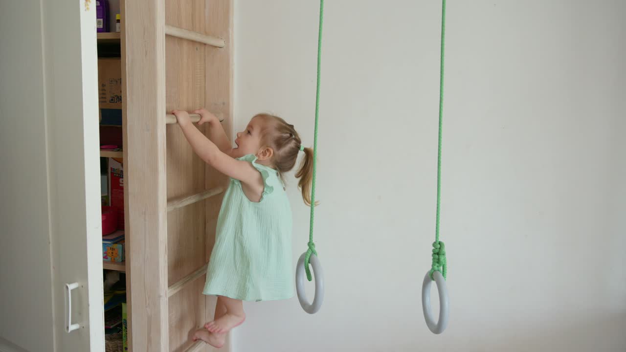 Bambina che sale su una scala di legno nella sala giochi di casa