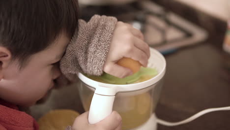 asian kid making natural fresh squeezed orange juice by himself