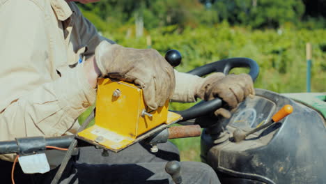 las manos del agricultor en el volante de un pequeño tractor controla el equipo agrícola en el campo