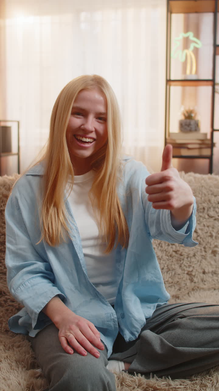Young woman thumbs up like at home smiling face support positive mood easy approval relaxed vibe