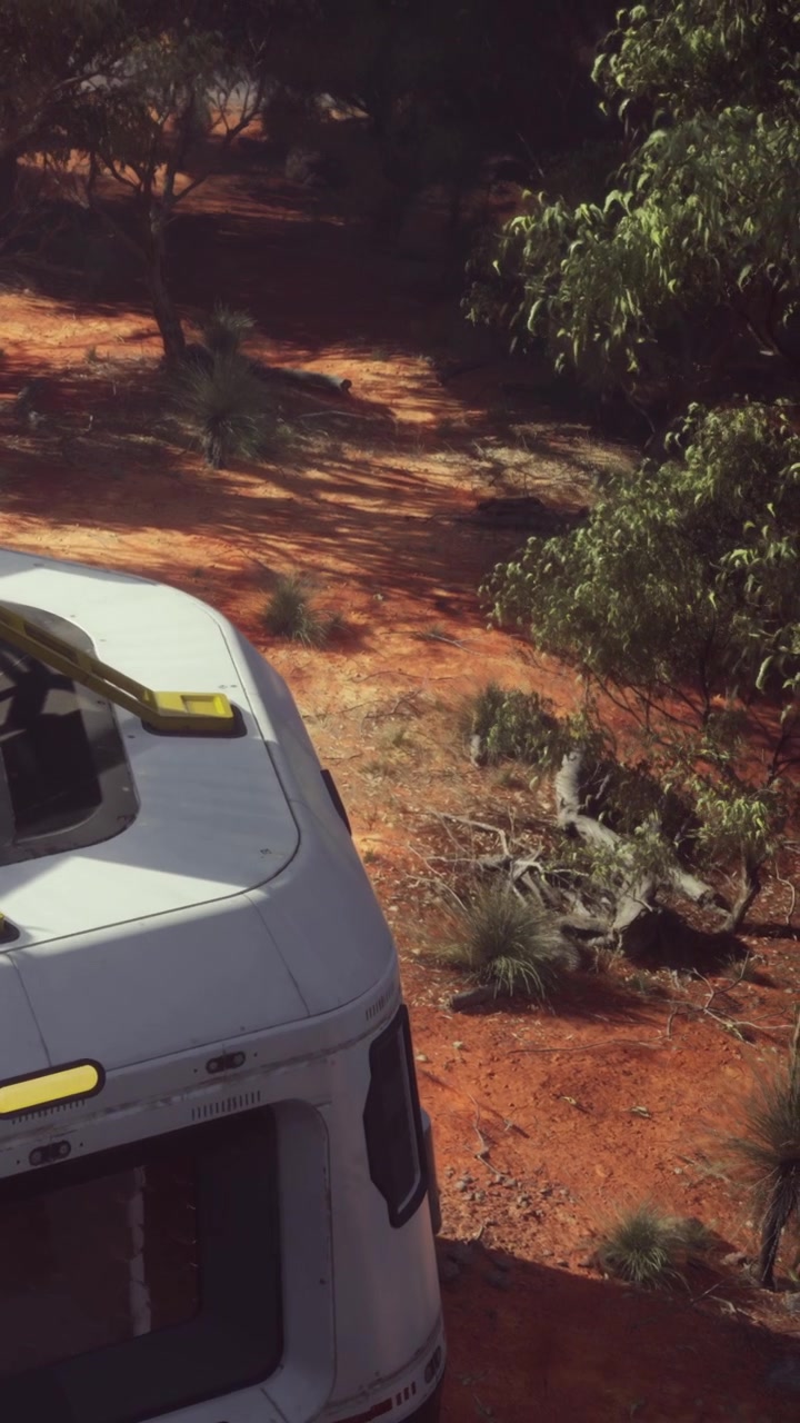 Un veicolo da viaggio è parcheggiato su una strada sterrata circondata da piante verdi.