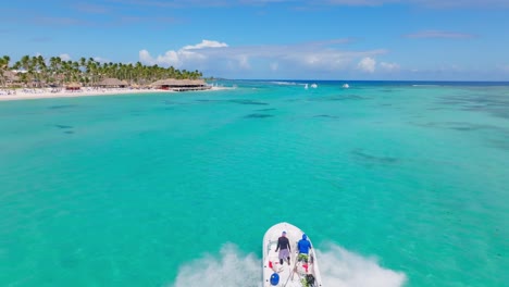 lancha rápida con dos personas a bordo navegando en aguas turquesas del océano de playa blanca, punta cana en república dominicana