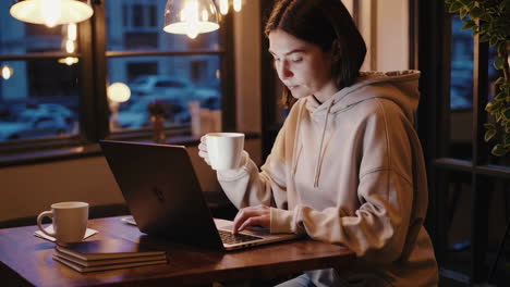 woman working on laptop in cafe at night