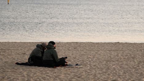 two men sitting on a beach together