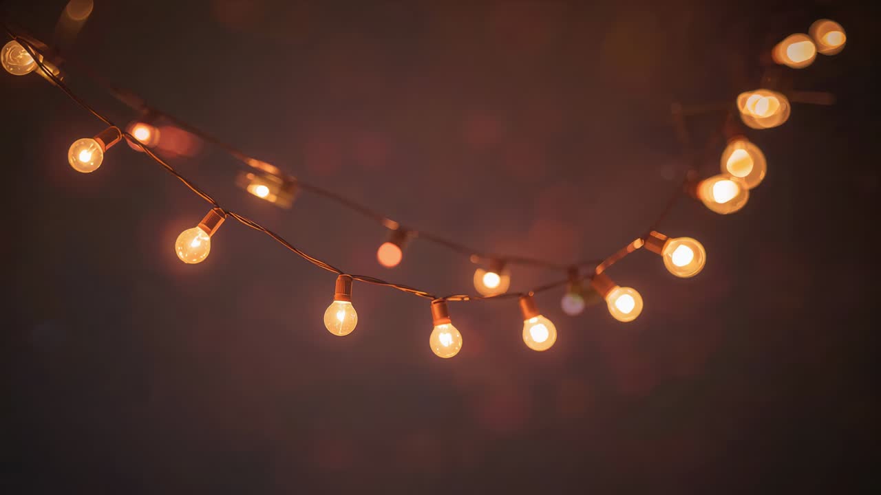 Spostamento leggero, filo di luce con lampadine a filamento che oscillano in un patio buio, assestandosi nell'inquadratura