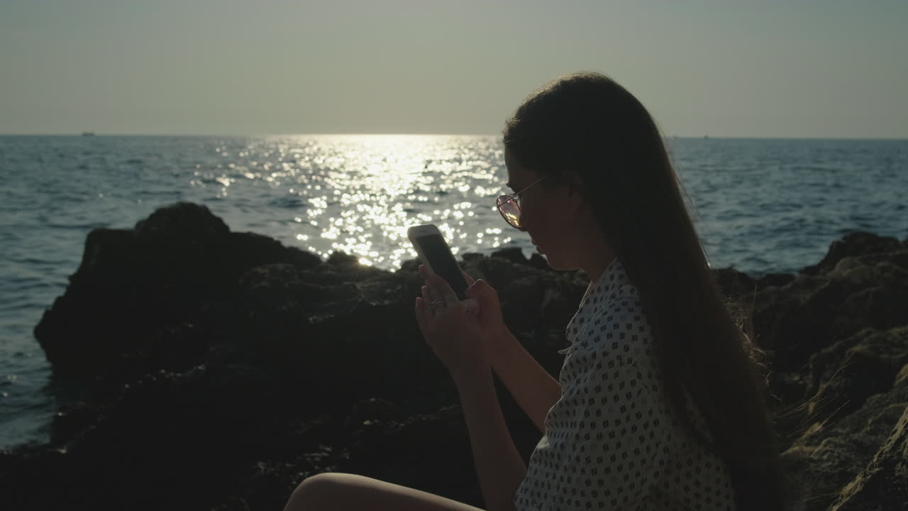 해가 지는 해변에서 드폰을 사용하는 소녀