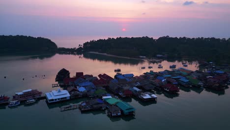 bang bao pier close up, traditional fishing stilt houses reflecting on calm sea at sunset in koh chang, thailand. beautiful aerial view flight fly reverse drone