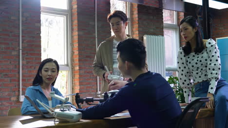 Team of innovative designers group of technology engage in workshop focusing on drone operations. A drone with camera is prominently displayed on table as participants discuss features and techniques