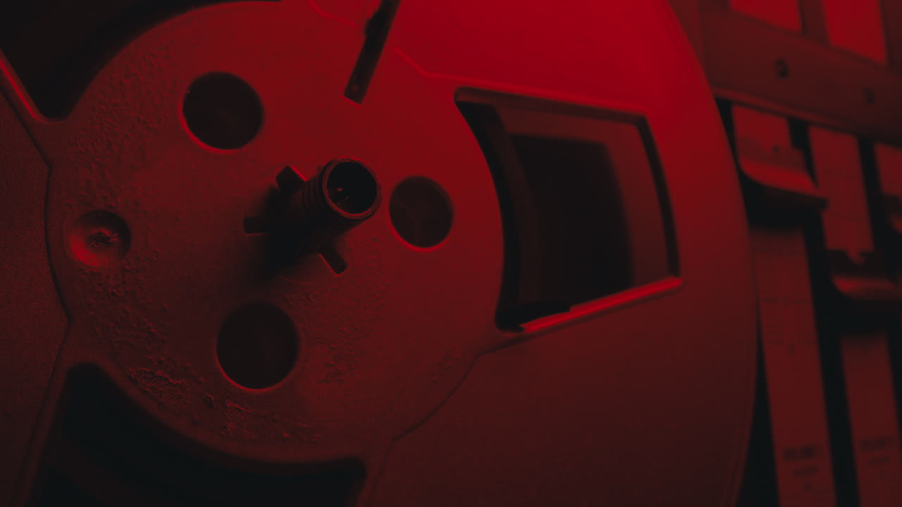 A close-up on a vintage tape recorder in a red blinking light