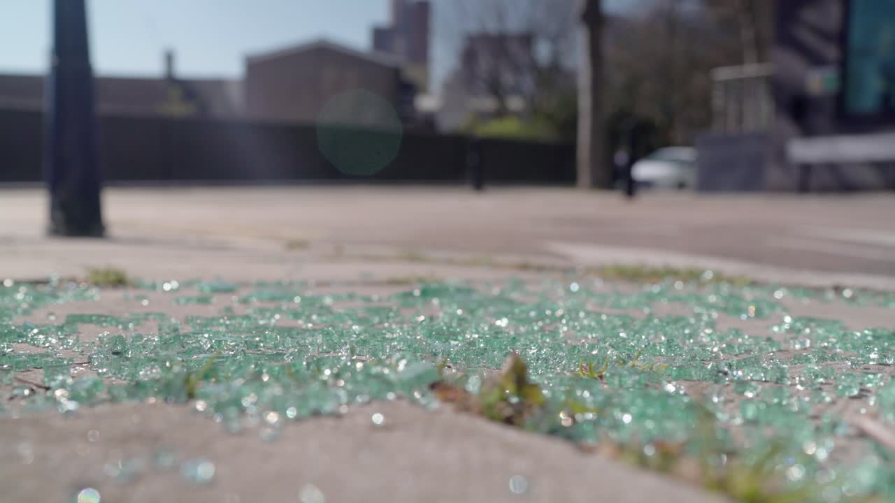 Morceaux de verre brisé au sol après un grave accident de voiture sur la route par une journée ensoleillée, tandis que la circulation continue en arrière-plan