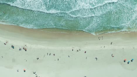 aerial view of crowded beach with turquoise water and waves