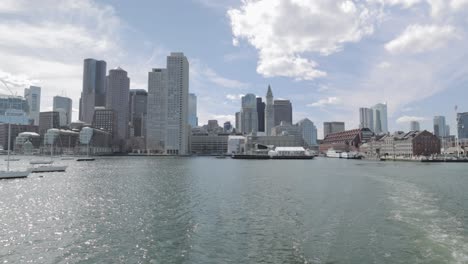 Vista-Del-Puerto-De-Boston-Del-Paisaje-Del-Centro-De-La-Ciudad-Desde-Un-Ferry-En-Un-Día-Soleado-En-4k