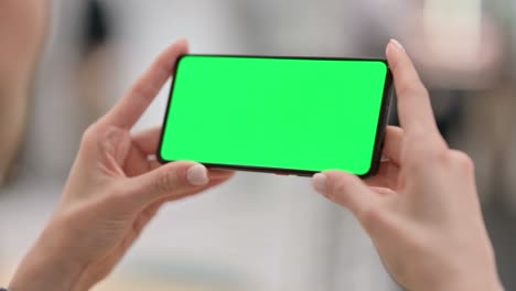 mujer mirando un teléfono inteligente con pantalla clave de croma verde