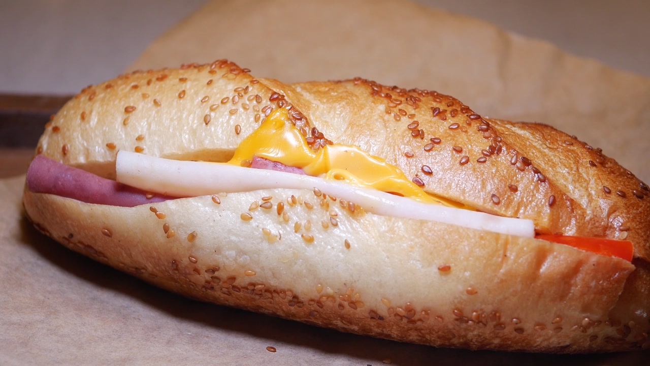 Hand Picking Up a Fresh Baguette Sandwich with Cheese and Deli Meat