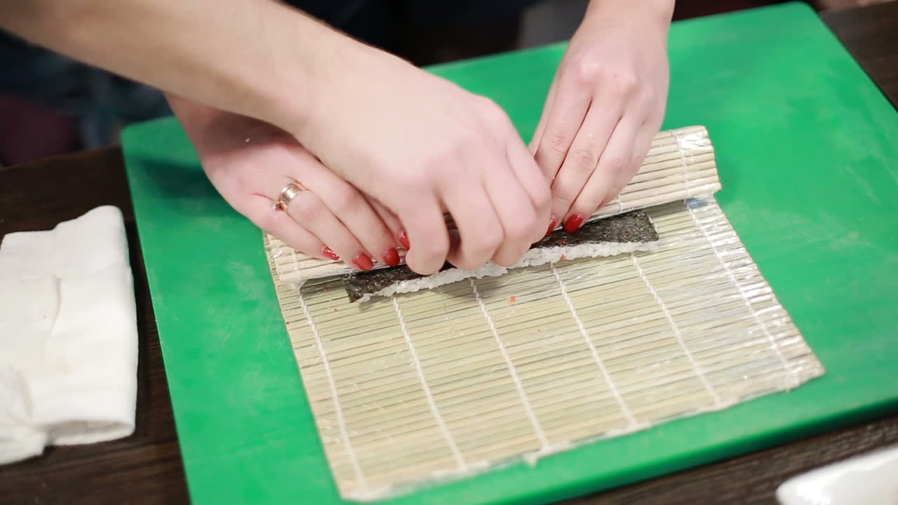 Preparing Sushi Set. Closeup of man chef putting japanese sushi rolls with rice