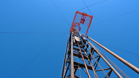 standing under the drilling derrick for producing oil or gas. low angle view at the tower with guyed mast on top.