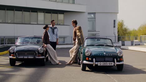 friends posing beside classic cars