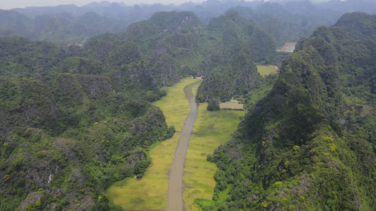 Drone backward reveal beautiful river with rice fields and limestone mountains on both sides Ninh Binh Viet Nam