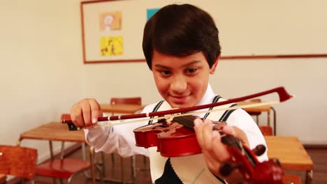 un alumno lindo tocando el violín en el aula