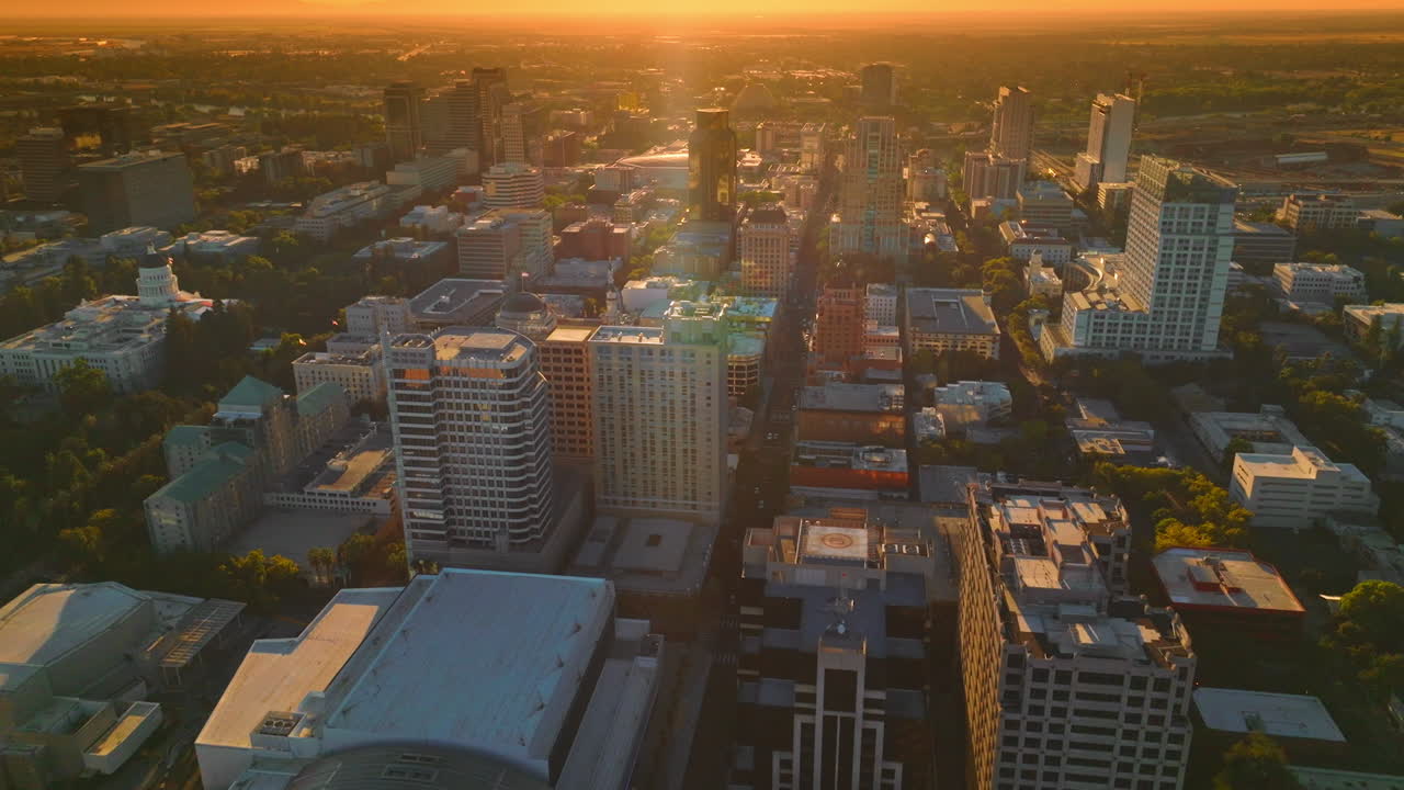 Beautiful architecture of modern American city in the rays of setting sun. Sacramento panorama at the backdrop of orange skies. Top view.