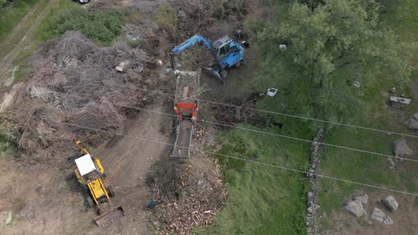 static flight with a drone visualizing the work of a vegetative matter crushing machine supported in its work by two other machines, one adds vegetable matter and the other removes what is crushed