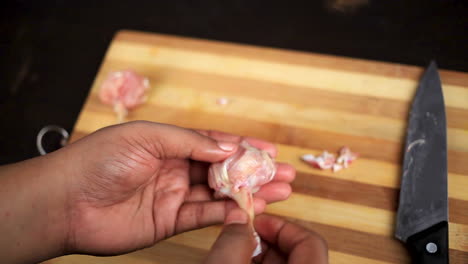 chef cortando alitas de pollo crudas con un cuchillo afilado y dándole forma de piruleta en una tabla de cortar