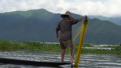 traditional myanmar fisherman using paddle with leg on inle lake