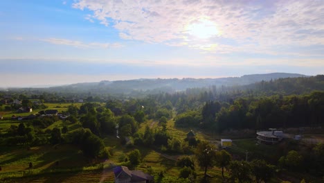 Aerial-view-over-homes-and-countryside-nature,-in-the-Carpathian-Mountains,-misty,-summer-day,-in-rural-Ukraine---dolly,-drone-shot