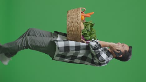 hombre llevando una canasta de verduras mientras habla por teléfono