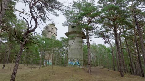 establishing aerial view of old soviet military concrete observation watchtower, pine tree forest, liepaja , military heritage, nordic woodland, low wide drone shot moving back