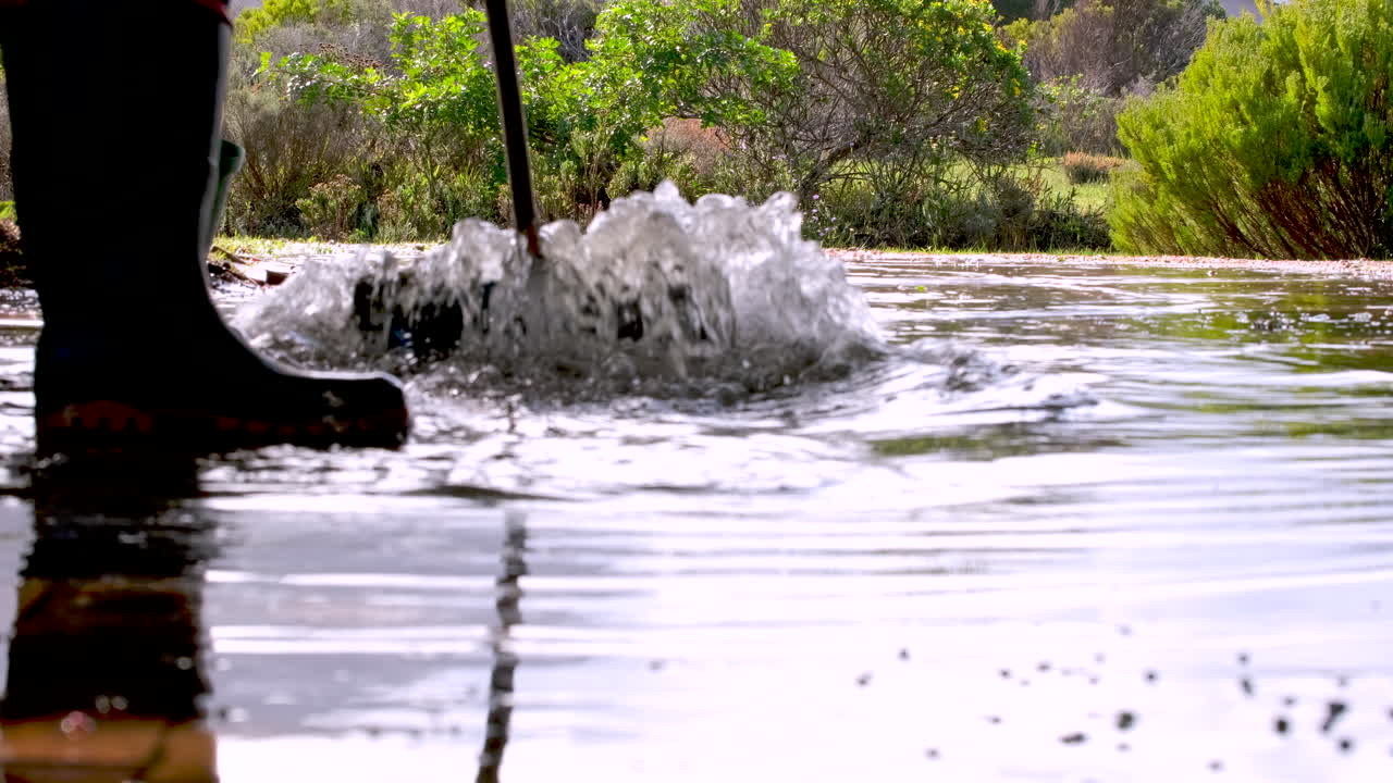 Low rear shot of man sweeping away standing rainwater from driveway after storm